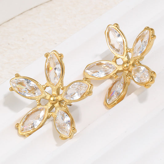 Gold earrings with clear gemstones on a light background