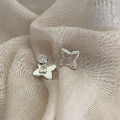 Close-up of white shell four-leaf clover stud earrings with zircon border by STUD on wooden background