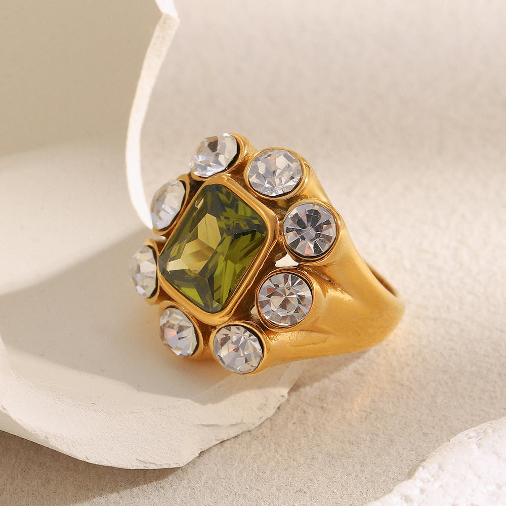 Close-up of 18K gold-plated stainless steel statement ring with green gemstone and white zircon crystals