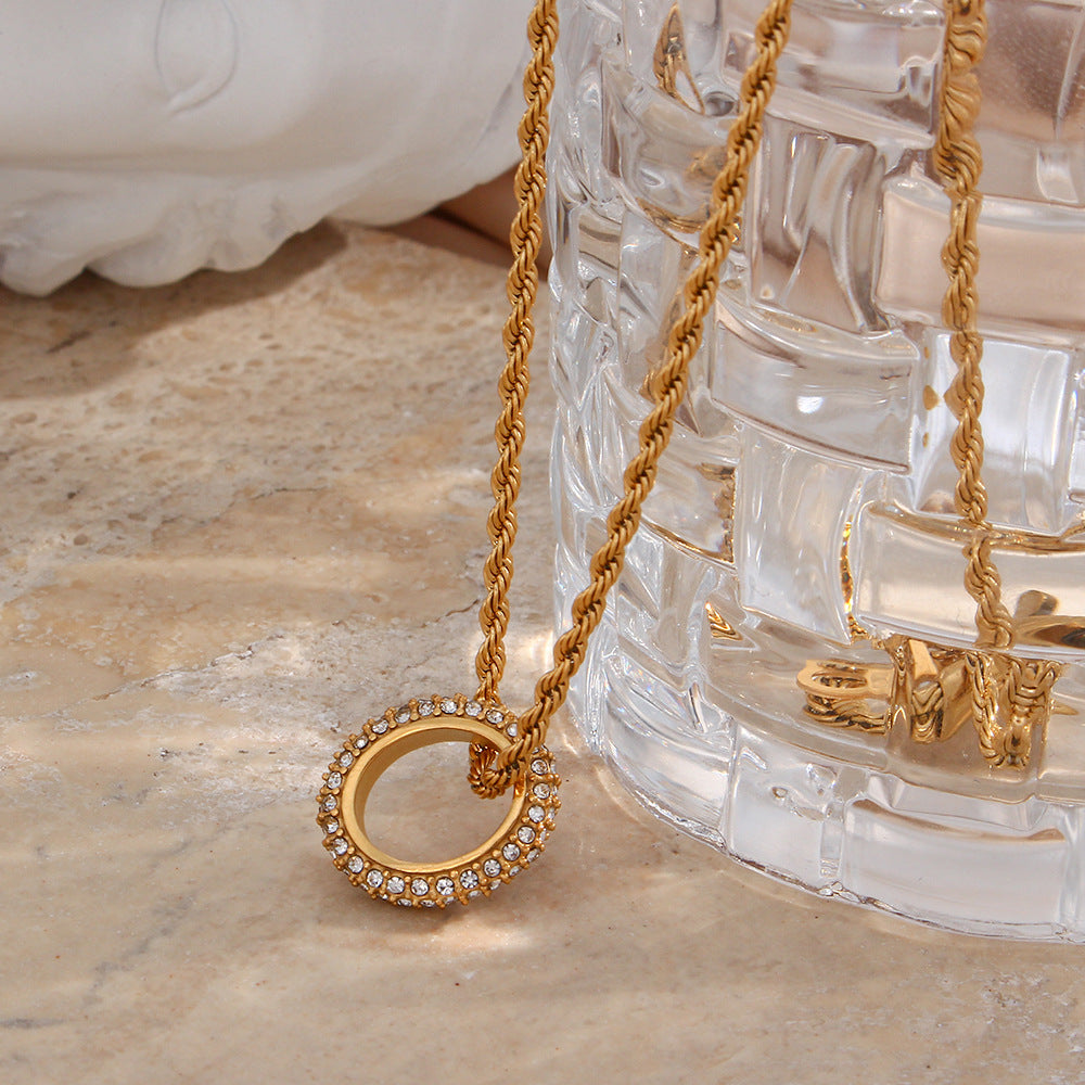 Twisted gold rope chain necklace with zircon circle pendant on display