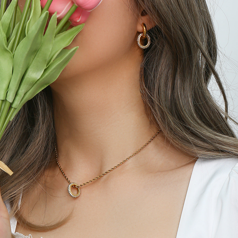 Twisted gold rope chain necklace with zircon circle pendant on display