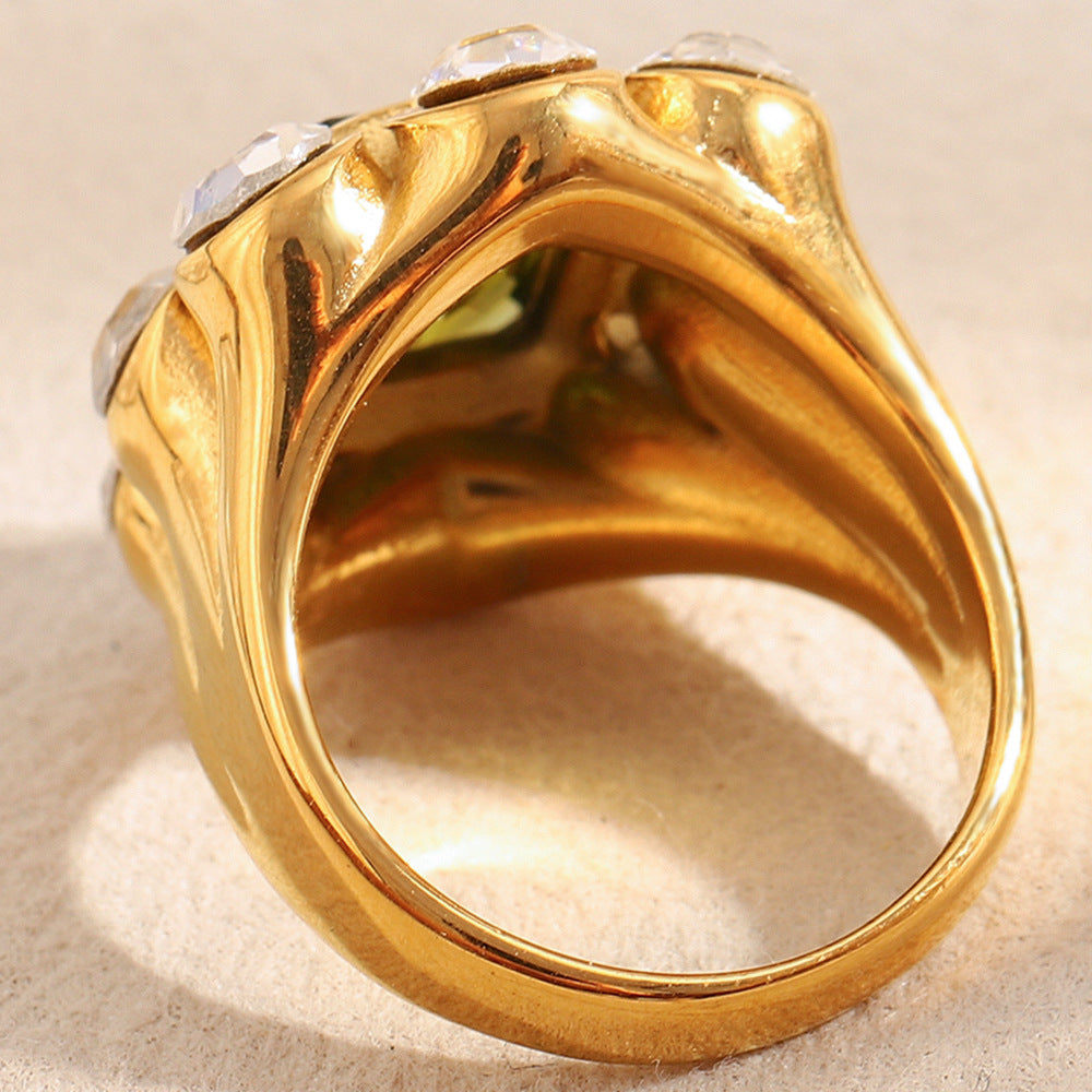 Close-up of 18K gold-plated stainless steel statement ring with green gemstone and white zircon crystals
