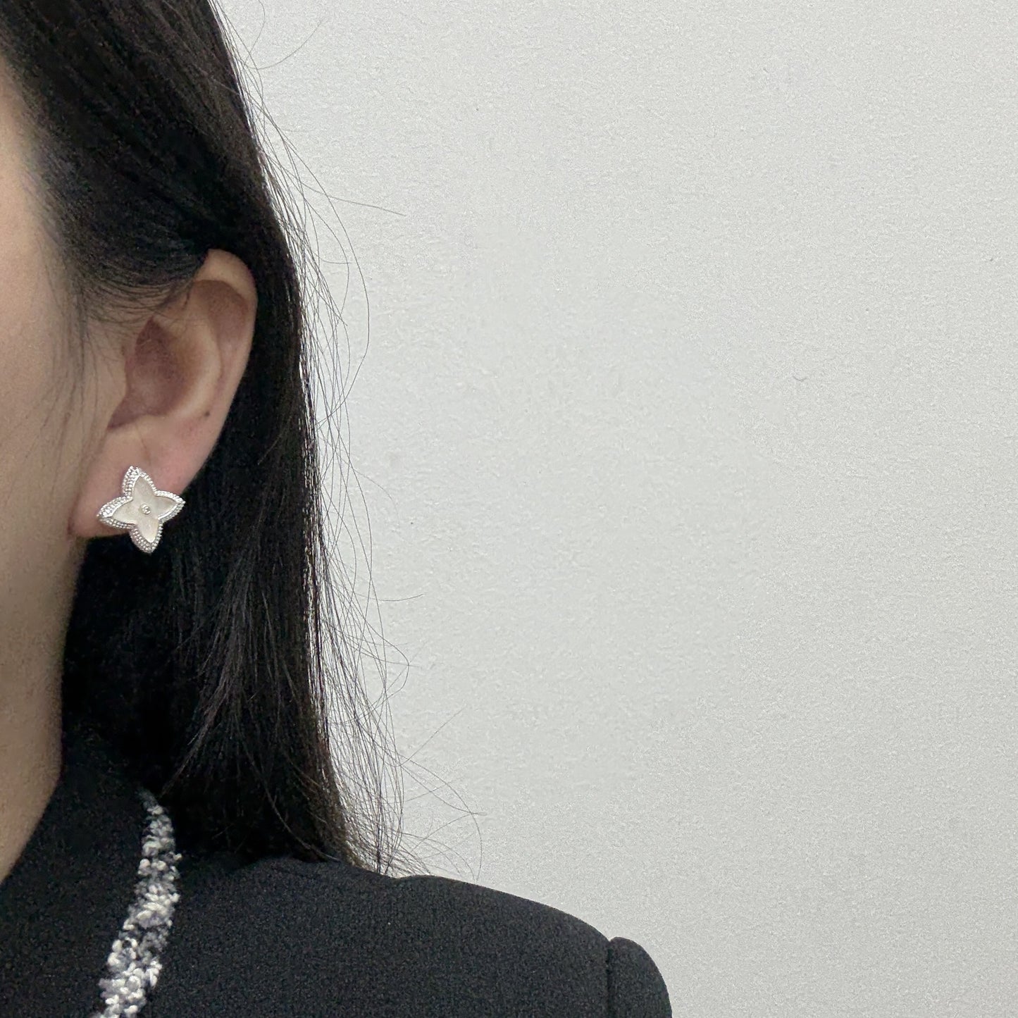 Close-up of white shell four-leaf clover stud earrings with zircon border by STUD on wooden background