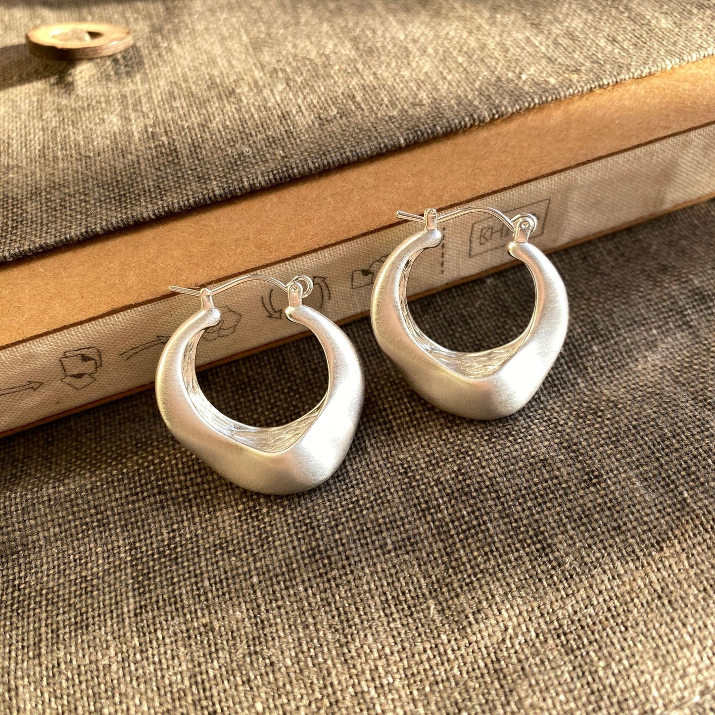 Brushed silver matte hoop earrings with modern irregular shape from STUD