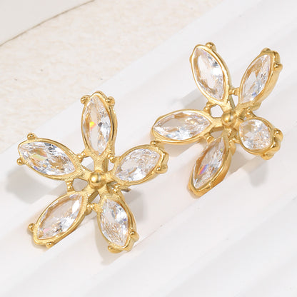 Gold earrings with clear gemstones on a light background