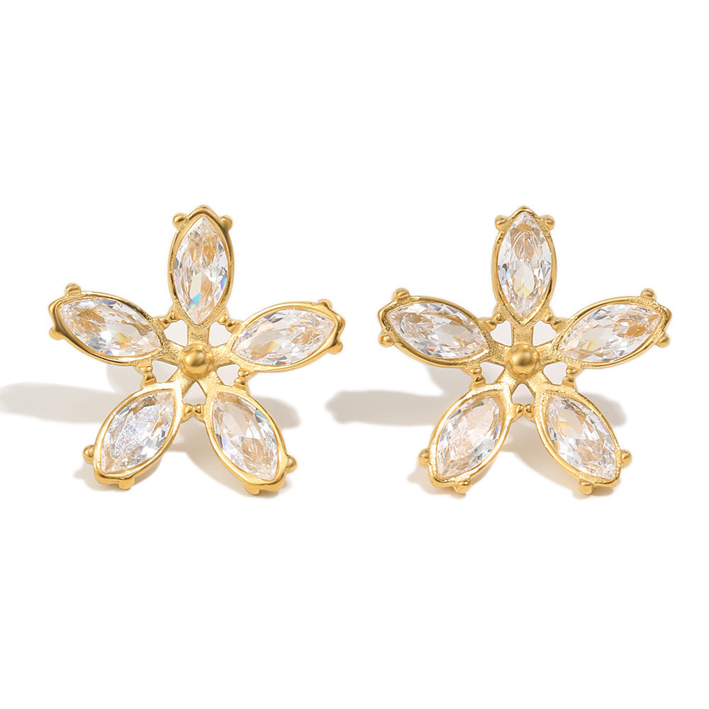 Gold flower-shaped earrings with clear gemstones on a white background